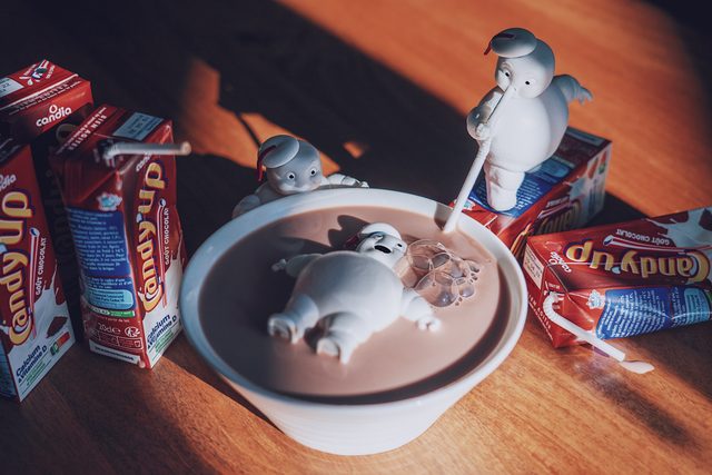 De petits bonshommes en guimauve se baignent dans un bol de chocolat chaud, entourés de briques de lait chocolaté